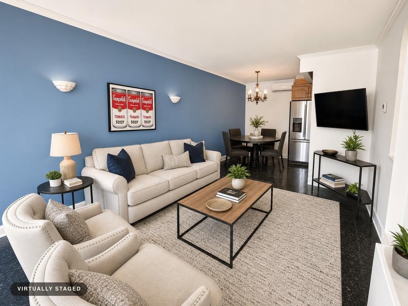 Modern living room with light beige sofa and chairs, blue accent wall, wood and black metal coffee table, and framed art above the sofa.