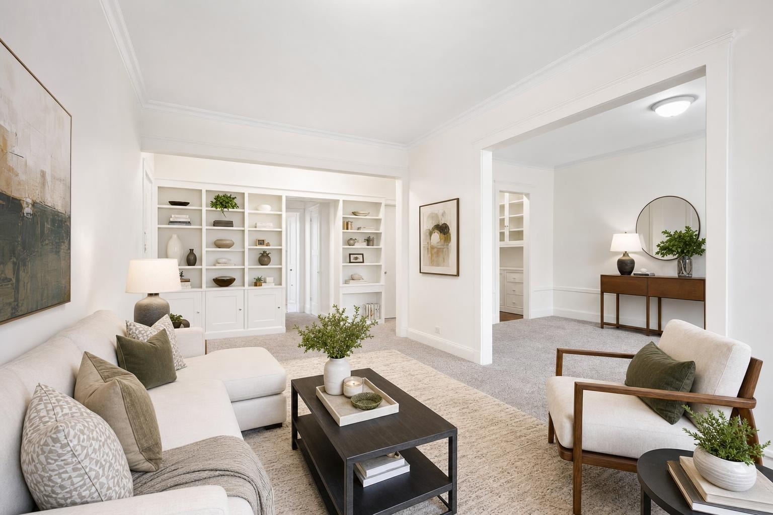Bright modern living room with a white sectional sofa, wood framed armchair, dark coffee table, and built-in white shelves.