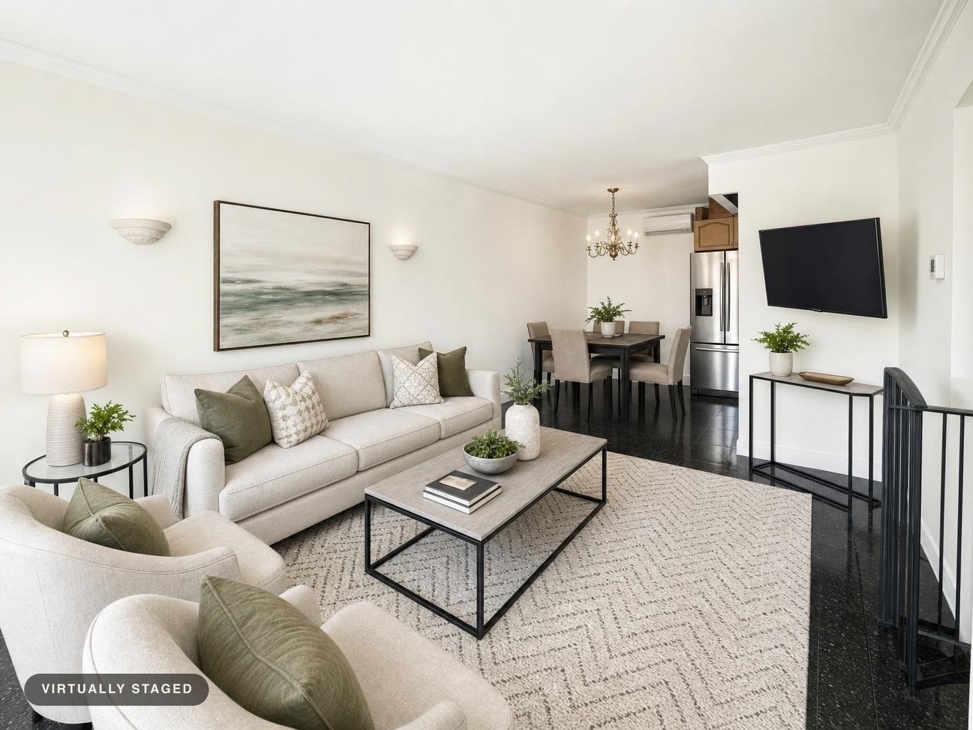 Modern living room with beige sofa, armchairs, rectangular coffee table, black metal-framed console under mounted TV, and dining area in background.