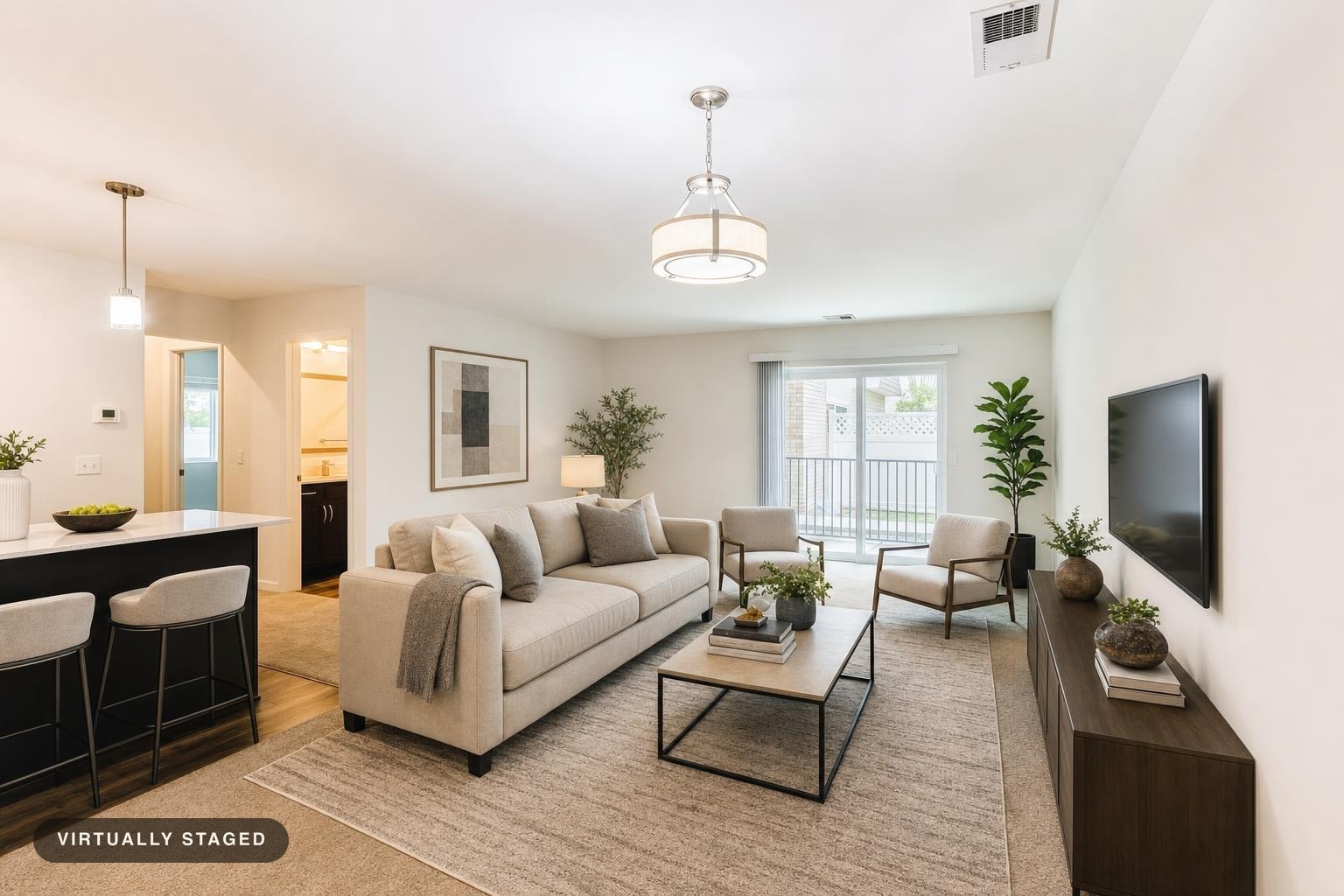 Modern living room with beige three-seat sofa, two light gray chairs, rectangular coffee table, dark wood media console, neutral rug, and wall art.