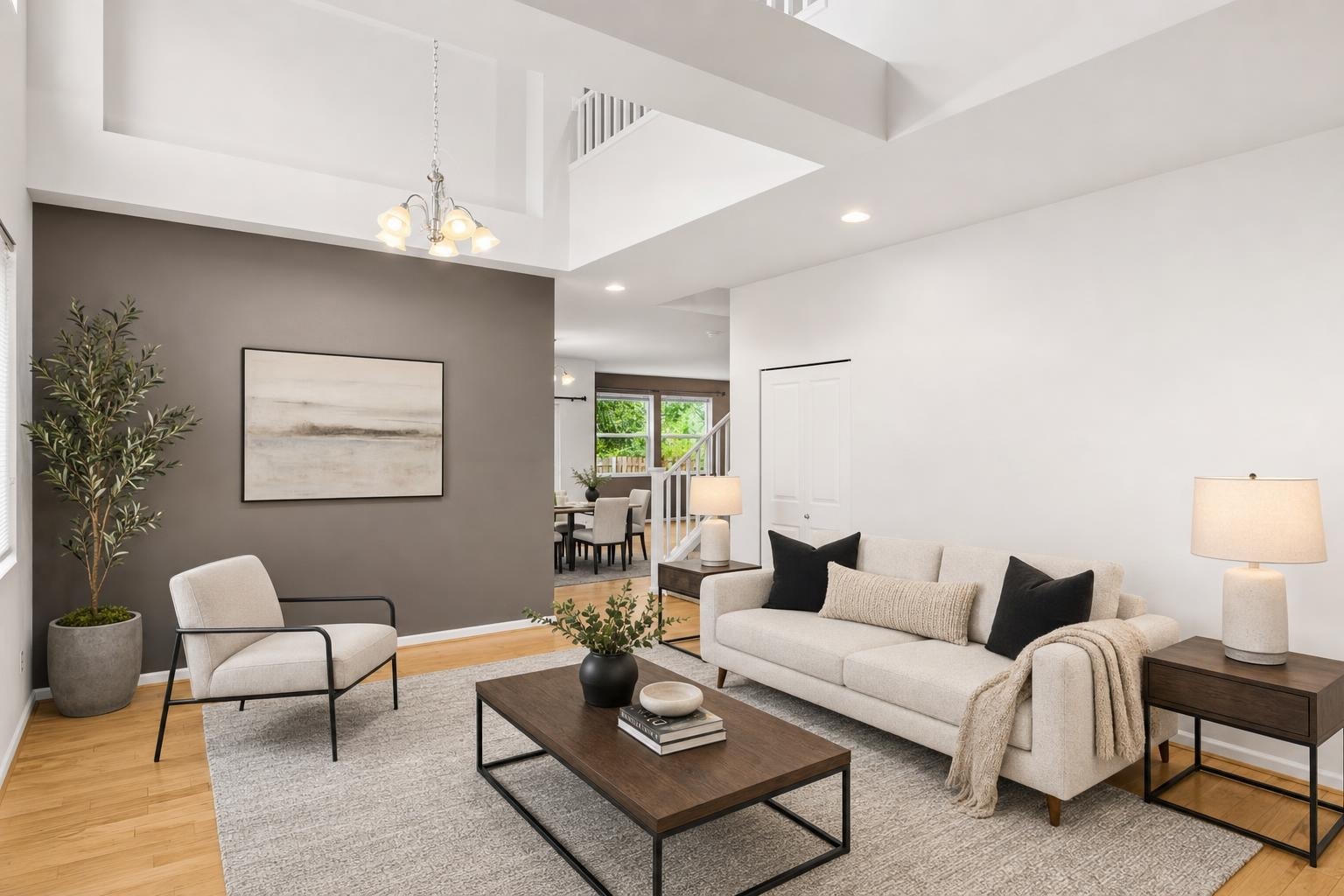 Modern living room with beige sofa, black metal frame chair, dark wood coffee table, and neutral decor.