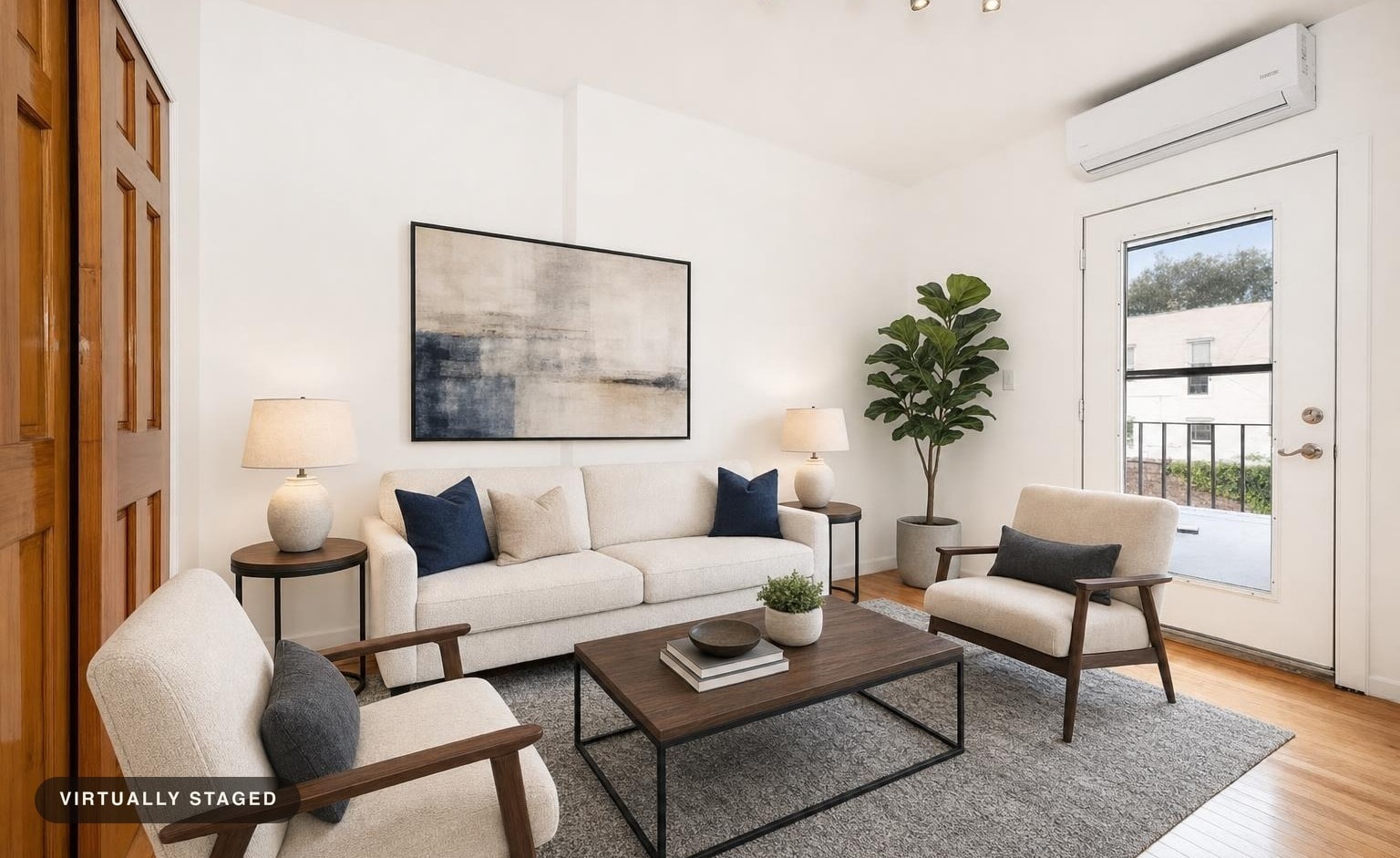 Modern living room with cream sofa, two armchairs with wooden arms, wood and metal coffee table, abstract art, and plants near glass door.