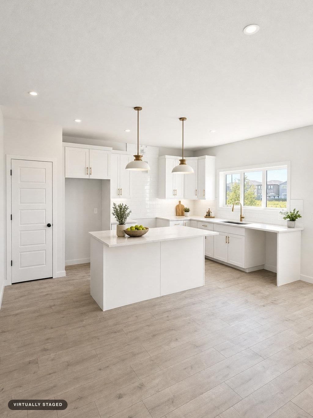 Bright modern kitchen with white cabinets, a central island, brass faucets, and two pendant lights, all on light wood flooring.