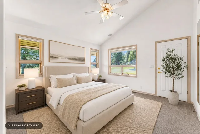 modern bedroom with beige upholstered bed, neutral bedding, dark wood nightstands, ceiling fan, potted plant, and large windows