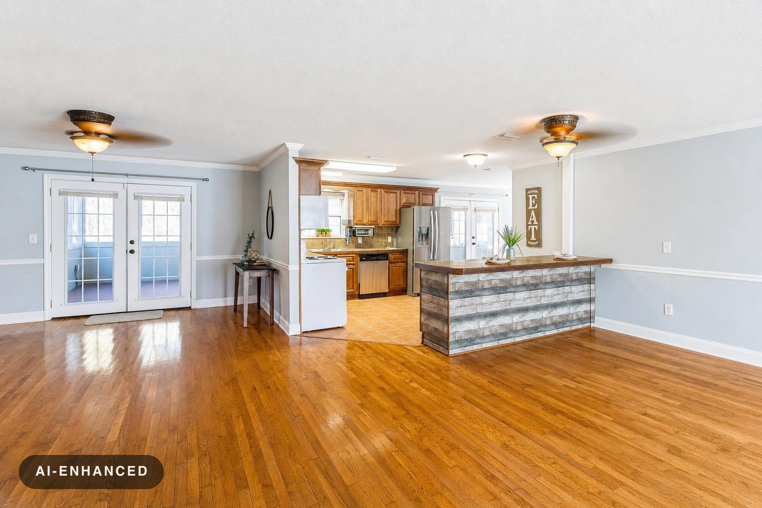 Open living room with hardwood floors, ceiling fans, and a kitchen with wooden cabinets and a rustic bar counter.