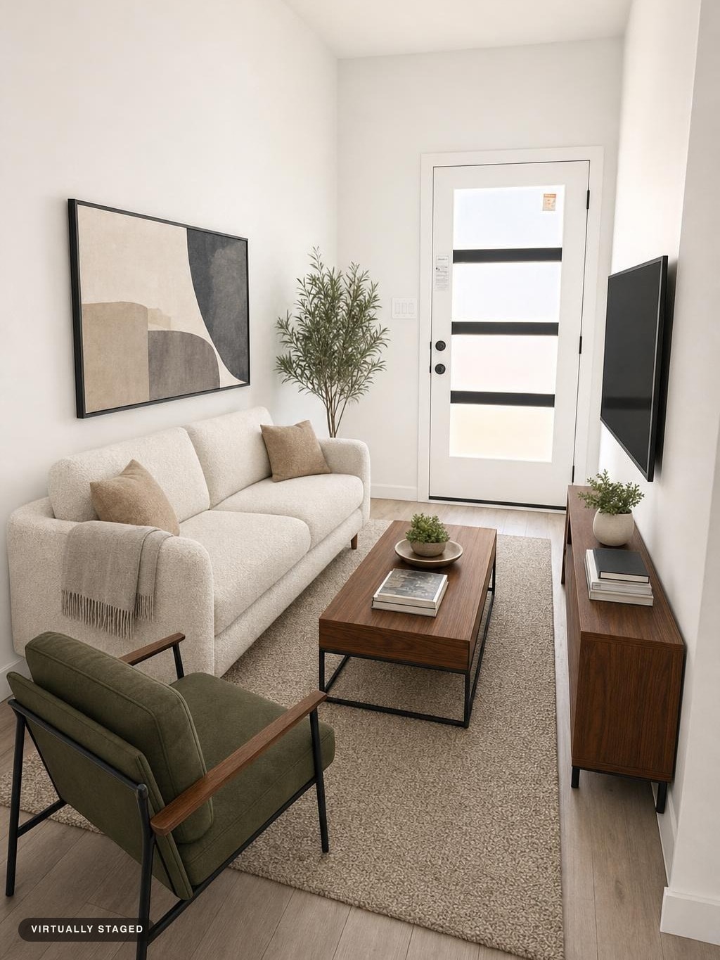 Modern living room with white sofa, green armchair, wooden coffee table and media console, abstract wall art and plant by door.