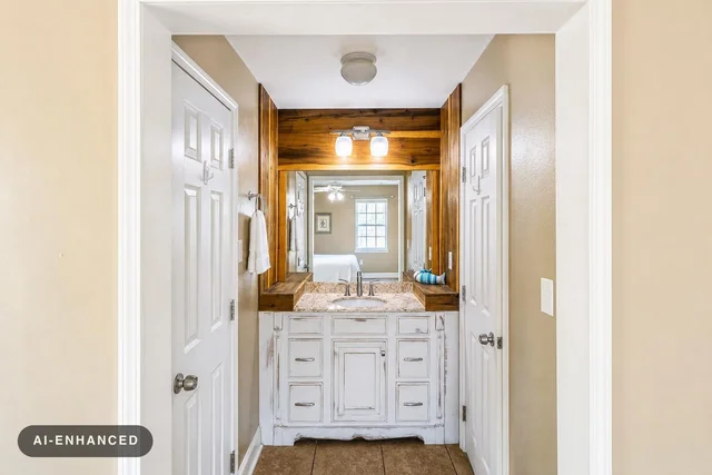 Rustic bathroom vanity with distressed white wood cabinet, granite countertop, wooden framed mirror, and two light bulbs above.