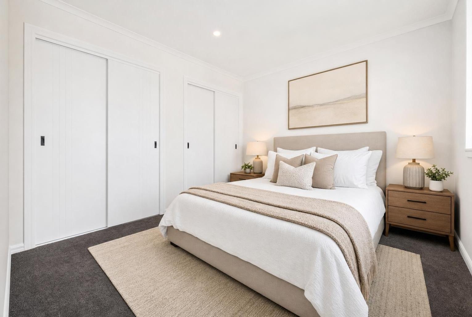 Modern bedroom with beige upholstered bed, white bedding, two wooden nightstands with lamps, and three sliding closet doors.